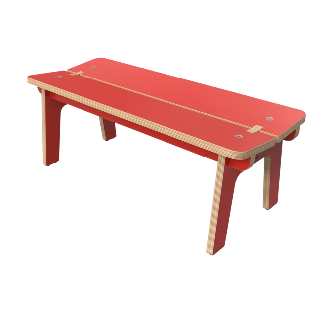 Moderní dřevěná lavice s červenou deskou a nohami, s odhalenými překližkovými hranami a jednoduchými, čistými liniemi. Lavice má minimalistický design a je sestavena pomocí viditelných drážkových a jazýčkových spojů.
